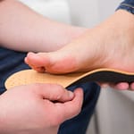 Custom Orthotics Chiropodist examining the sole of a patient's foot during a biomechanical assessment for orthotics in Oakville